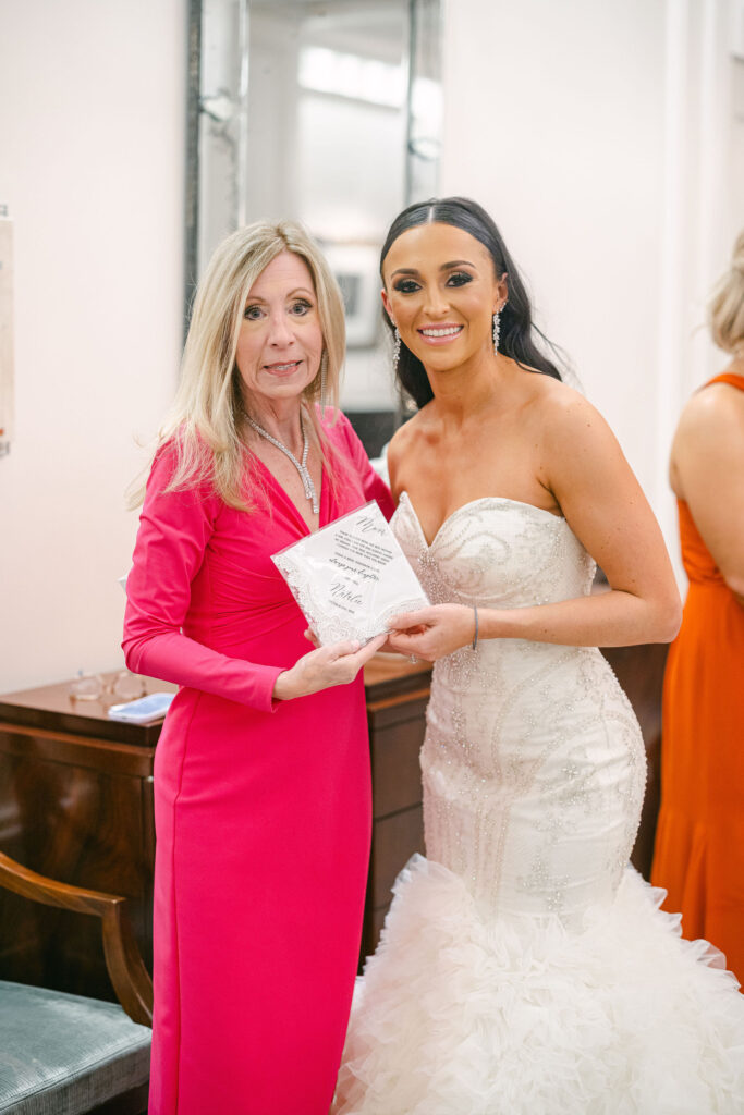 Mother of the bride and the bride holding hands and smiling