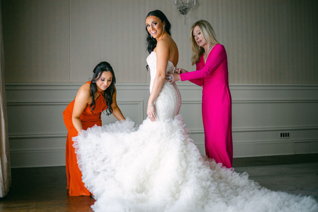 mother of the bride and sister of the bride helping the bride get dressed