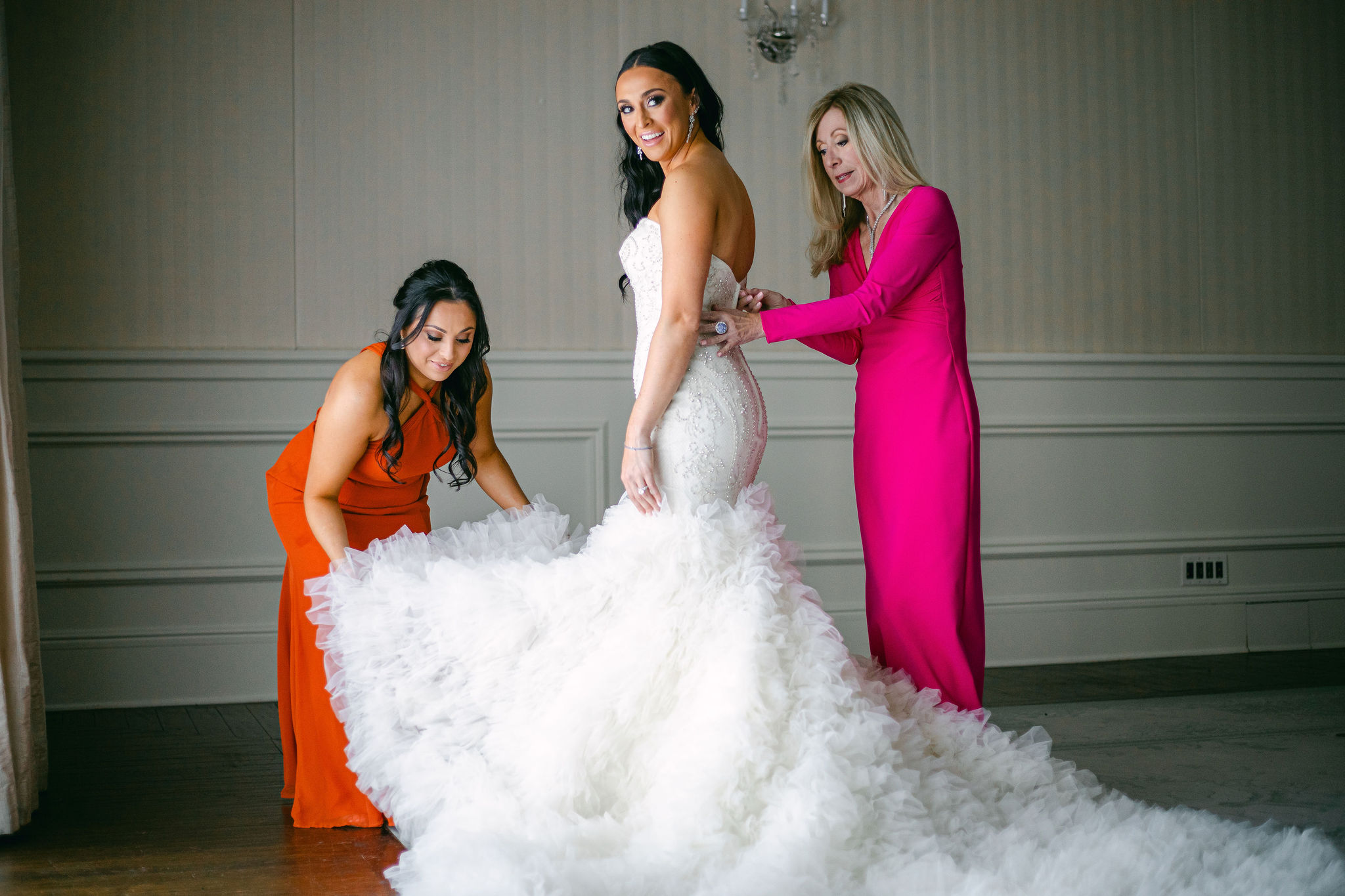 mother of the bride and sister of the bride helping the bride get dressed